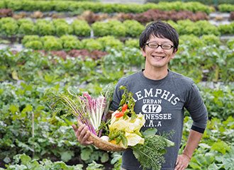 写真：農園にて野菜をとる章隆さん