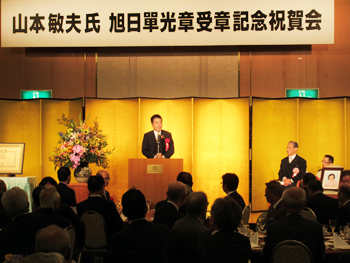 三日月知事が山本敏夫氏叙勲祝賀会に来賓として祝辞を述べる様子。