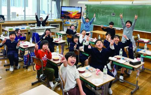 石川県能登町にある柳田小学校の教室で簡易な昼食を楽しそうに食べる子どもたちの写真