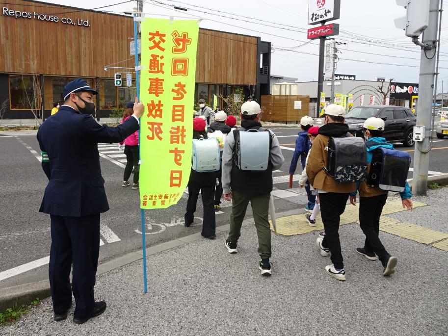 横断歩道を渡る児童と見守る警察官