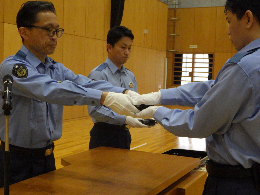 学校長から手錠を受け取る学生