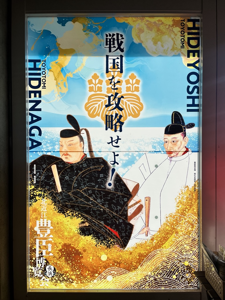 豊臣秀吉と豊臣秀長のイラストが描かれたポスター。中央に戦国を攻略せよ!と書かれている。