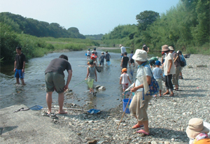 川で生き物の観察会をしている画像です。