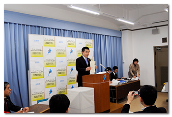 俳句東風受けて 山越え飛べと この予算を説明する様子