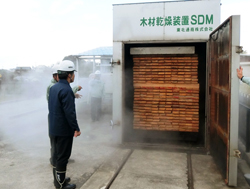木材乾燥装置SDMの前で話す大津・南部地域木材供給協議会の方々